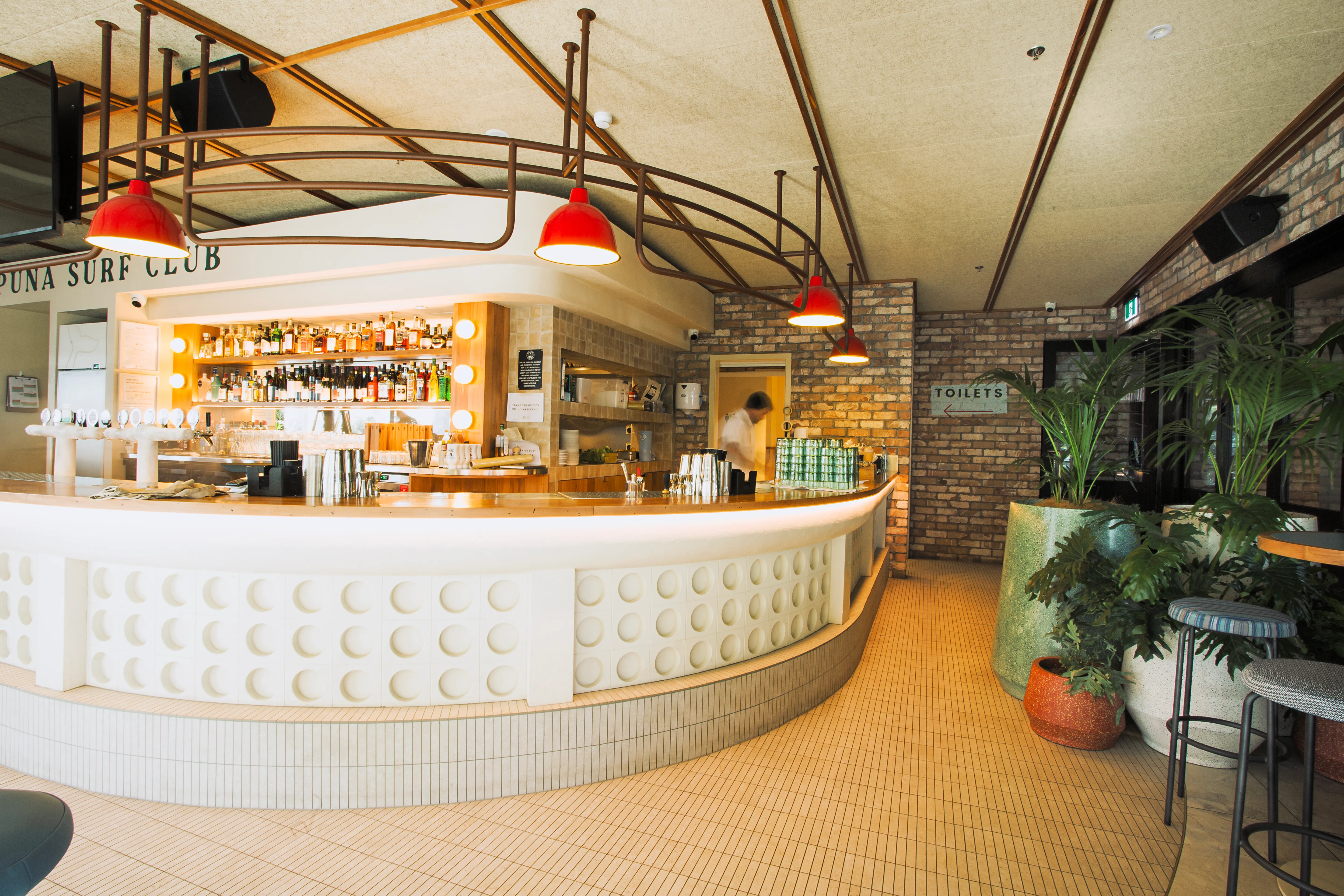 Takapuna Surf Club bar with red pendant lights and beach views, Auckland